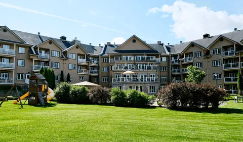 Residence with balconies overlooking a lawn, shrubs and a wooden play structure