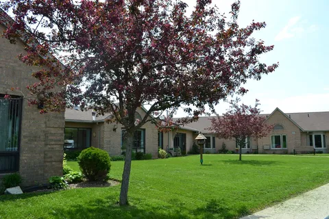 Single-storey residence surrounding a lawn with trees and a birdhouse.