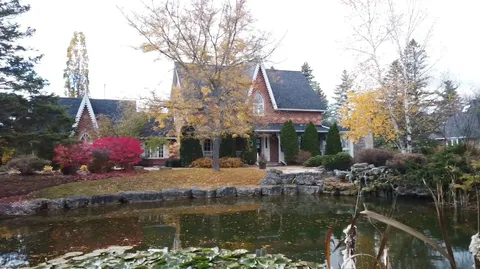 Brick residence with a pond, trees and planting beds
