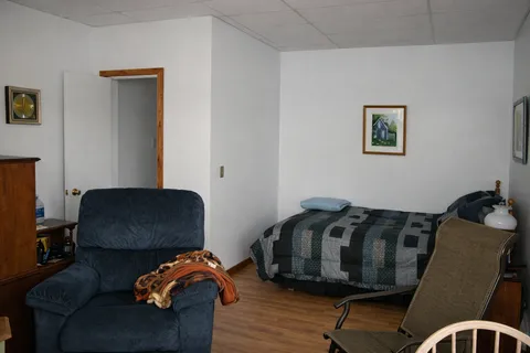 Bedroom with a single bed, blue recliner and framed landscape pictures