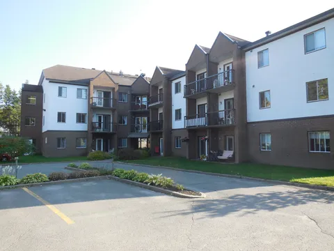 Three-storey residence with balconies, landscaped beds and a paved parking area