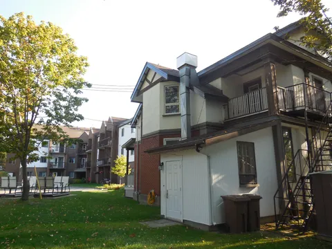 Rear of the residence with an exterior staircase, lawns and outdoor chairs