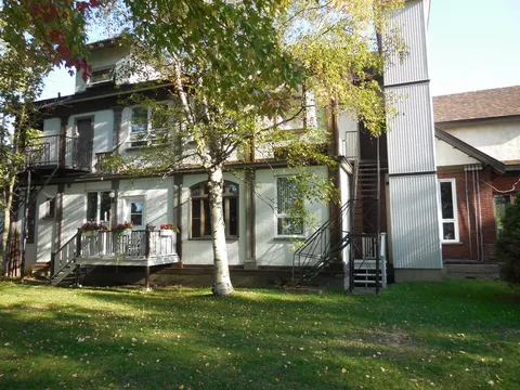 Residence with porches, an exterior staircase and a tree-shaded lawn