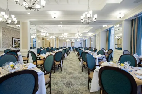 Dining tables with blue chairs beside tall windows