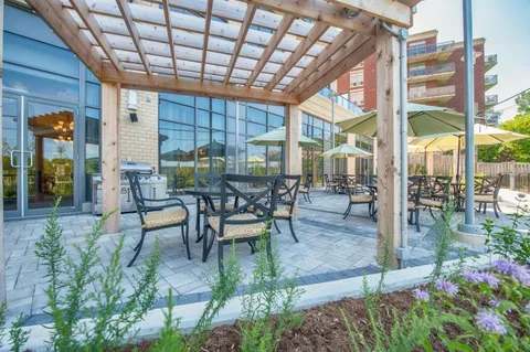 Patio tables and chairs beneath a wooden pergola