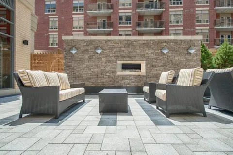 Outdoor sofas around a stone fireplace on a paved terrace