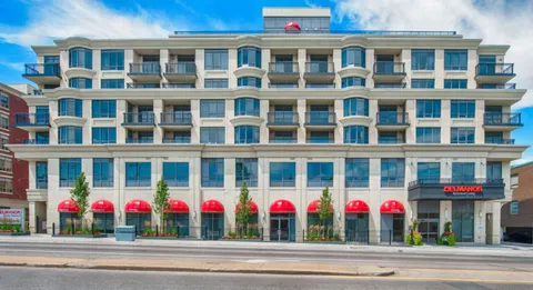 Building facade with balconies, red awnings and a broad sidewalk