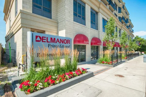 Building facade with a covered entrance, shrubs and flower beds