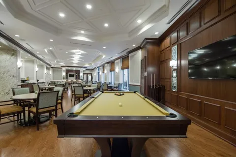 Room with a billiards table, bar stools and wooden cabinetry