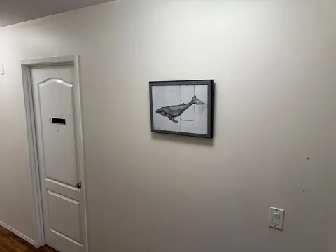 Hallway with a white door and a framed picture of a whale