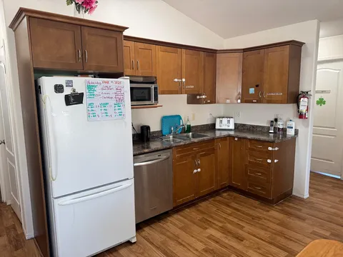 Kitchen with wooden cupboards, a refrigerator, a microwave and a dishwasher
