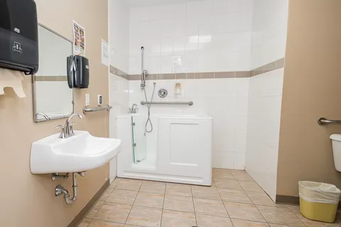 Accessible bathroom with a sink, raised bath and grab rails