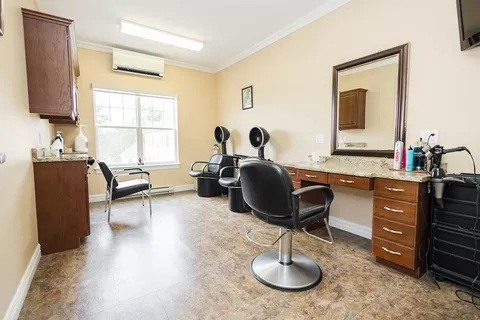 Hair salon with black chairs, hood dryers and a large mirror