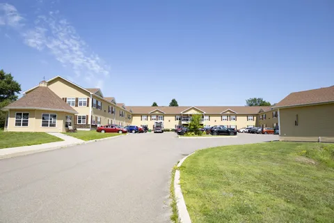 Yellow residence buildings around a paved driveway and lawn