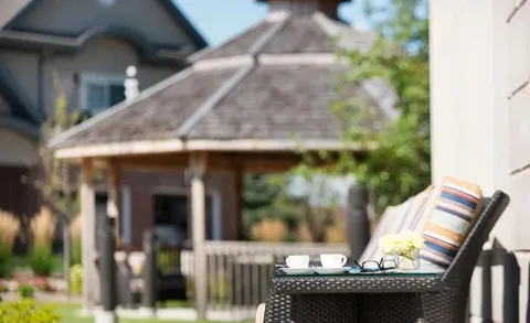 Outdoor lounge chair with a gazebo and garden behind it.