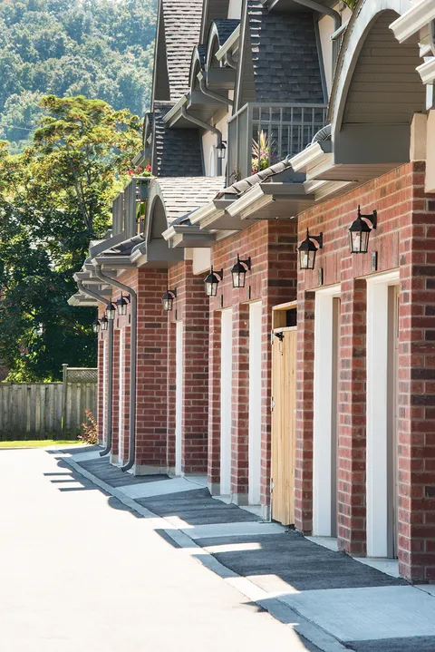 Brick townhouse facades along a paved walkway.