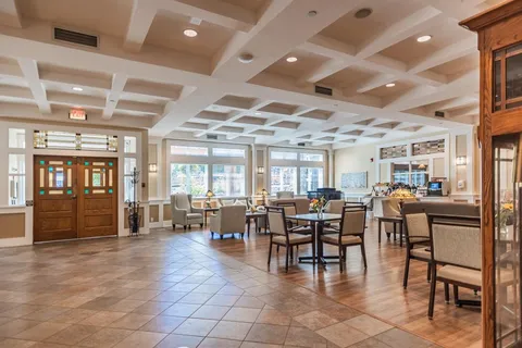 Large room with tables, chairs, armchairs, a counter and large windows