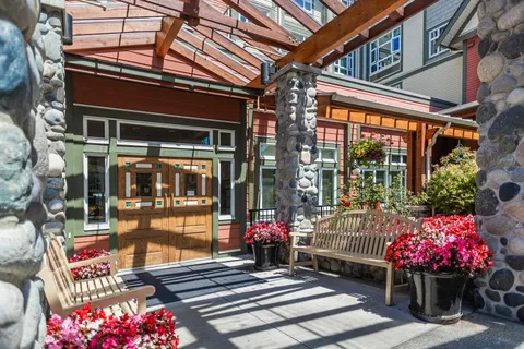 Covered entrance with a bench, flower planters and glass doors