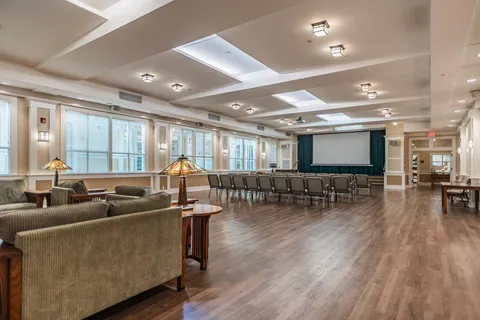 Large room with rows of chairs, sofas and a blank projection screen