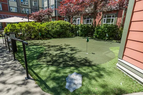 Putting green beside landscaped shrubs and trees