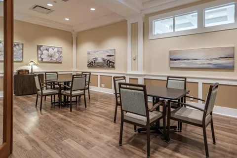 Dining room with square tables, upholstered chairs and framed artwork