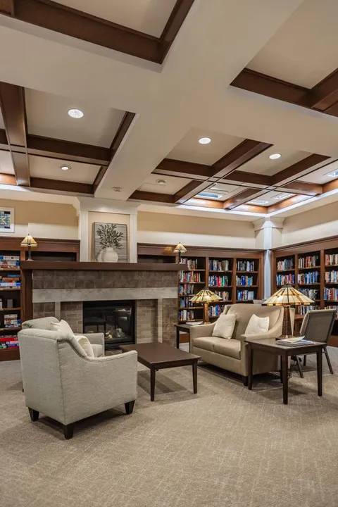 Library seating around a fireplace with bookshelves and table lamps