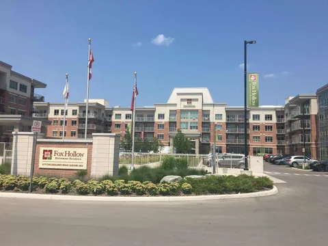 Multi-storey brick building with a central entrance, flagpoles and landscaped beds