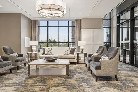 Armchairs and a sofa around a coffee table beneath large windows