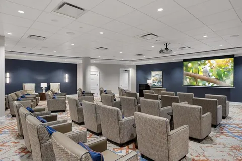 Rows of upholstered chairs facing a screen showing a bird on a branch