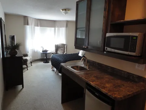 Suite sitting area and kitchenette beside a window.