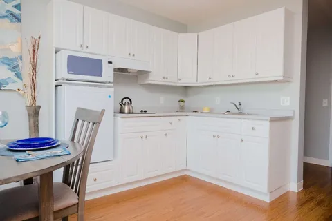 Kitchenette with white cabinets, a microwave, refrigerator and sink