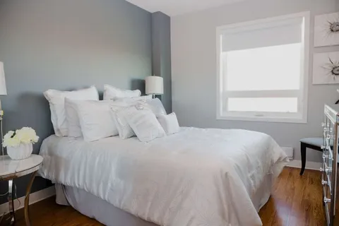 Bedroom with a pale bedspread, dark furniture and a window