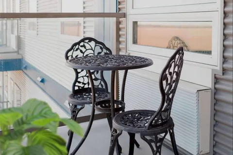 Balcony table and chairs beside white siding and a railing