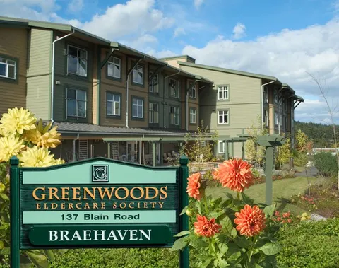 Residence building behind a green sign and orange flowers