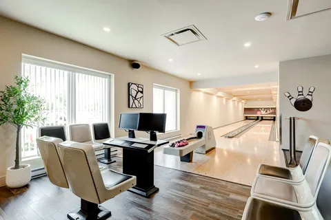 Bowling lanes with pale chairs, blank screens and a rack of balls