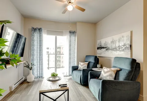 Two blue recliners beside a coffee table, television and balcony door