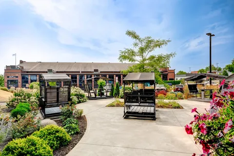 Garden with flowering beds, paved paths and covered swing seats