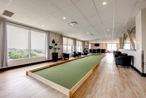 Indoor bocce lane beside large windows and black seating