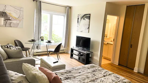 Suite with a bed, sofa, glass dining table and television