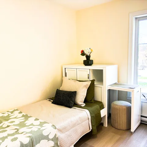 Bedroom with a single bed, white cabinets and a desk