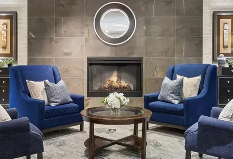 Blue armchairs and a coffee table beside a tiled fireplace.