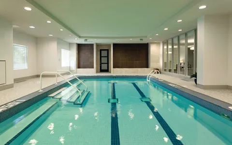 Indoor swimming pool with entry steps and large windows.