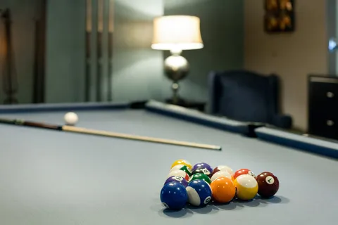 Billiard balls on a pool table beside lounge seating.