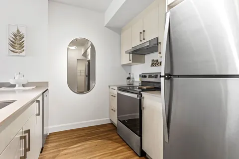 Kitchen with white cabinets, stainless appliances and an oval mirror