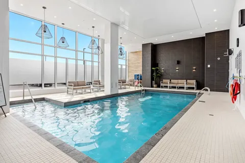 Indoor swimming pool with deck seating and large windows
