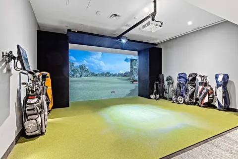 Indoor golf simulator with golf bags and a projected course view