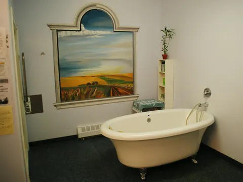 Bathing room with a freestanding tub and a framed landscape.