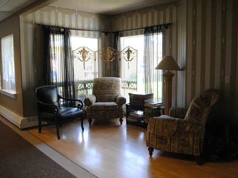Windowed sitting area with armchairs and curtains.