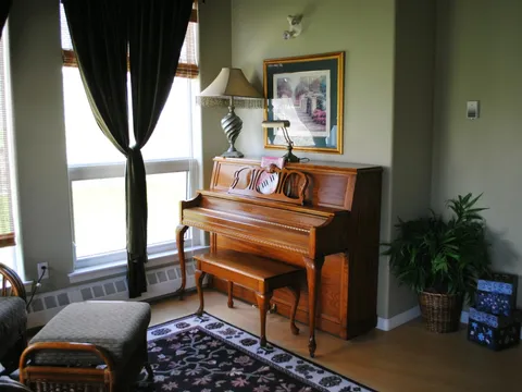 Piano beside windows in a shared room.