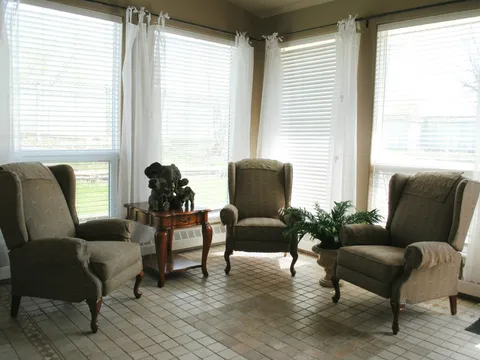 Sunroom with armchairs and large corner windows.